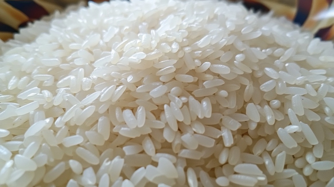 Close-up image of uncooked white long-grain rice, possibly Jasmine or Basmati, showcasing the subtle differences in texture and shape